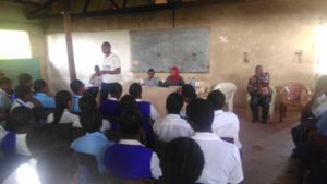 A young man standing in front of students talking with them