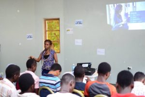 A young lady standing infront of a crowd presenting